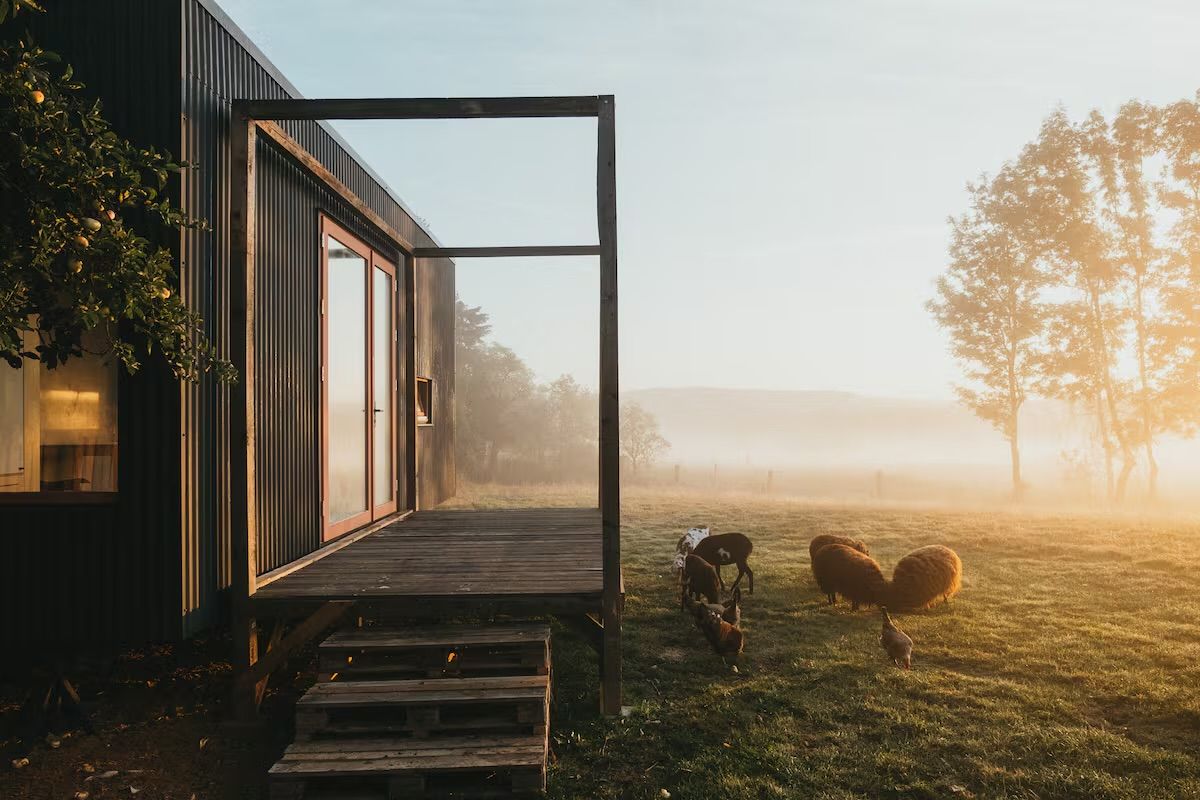 Tiny house s terasou v podzimní mlze při východu slunce